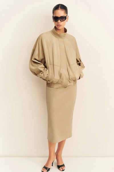 Front full-length view of a model wearing the relaxed-fit Shona Joy Ernest faux suede bomber jacket in sand styled with a matching midi skirt and sunglasses.
