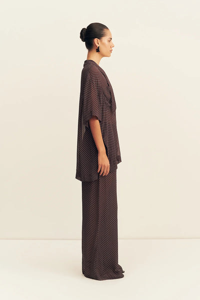 A side-profile studio shot of the unlined georgette pants on a model, demonstrating the lightweight drape, structural straight-cut side seams, and fluid movement.