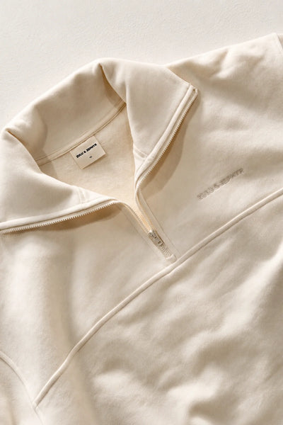 Flat-lay detail view of the collared collar, zip closure, and tonal embroidered chest logo of the Zulu & Zephyr Sport Sweat Shirt Fleece in Cream.