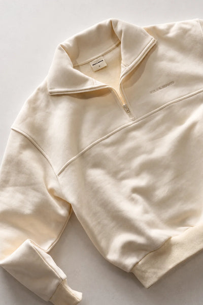 Flat-lay overview shot displaying the ribbed hem, cuffs, chest seam, and collared quarter-zip design of the Zulu & Zephyr Sport Sweat Shirt Fleece in Cream.