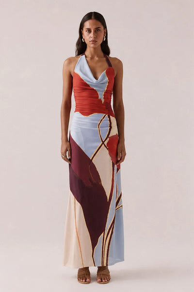 Full-length front view of a model posing in the Vere Kalea halter neck maxi dress in Blue Bloom with a draped cowl neckline and abstract floral stretch mesh pattern.