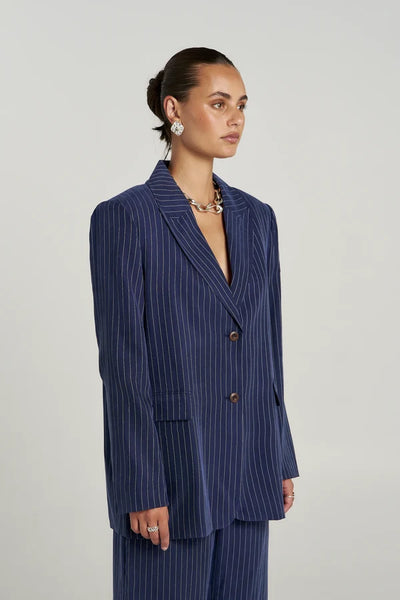 Three-quarter front view of model wearing the Summi Summi OS Blazer in Navy Pinstripe, showing notch lapels, double-button front closure, and flap pockets.