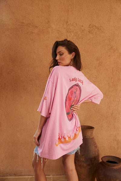 Three-quarter back view of Sabbi The Very Oversized Lucky Mermaid Tee in Bright Pink, highlighting the "Lady Luck" graphic and flame print across the back hem.