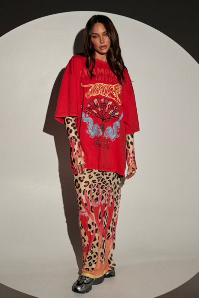 Full-length front studio portrait of model Tilly wearing the red SABBI Very Oversized Champagne Tattoo Tee featuring tiger, fan, and dragon graphics, layered over a leopard and flame print mesh top.