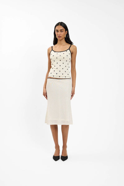 A front lifestyle campaign portrait focusing on the mesh camisole top in Ivory Polka, highlighting the delicate scoop neckline and soft daylight accentuating the black polka dot motif.