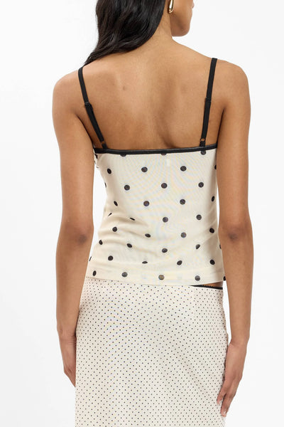 A back-angle lifestyle profile view of the ivory polka dot camisole, highlighting the thin adjustable shoulder straps resting smoothly against a low-cut back neckline.