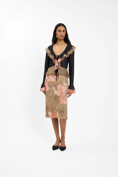 A front studio portrait of a model wearing the sheer frill cardigan over a dark bralette, highlighting the delicate ruffle placement along the plunging neckline and down the center front.