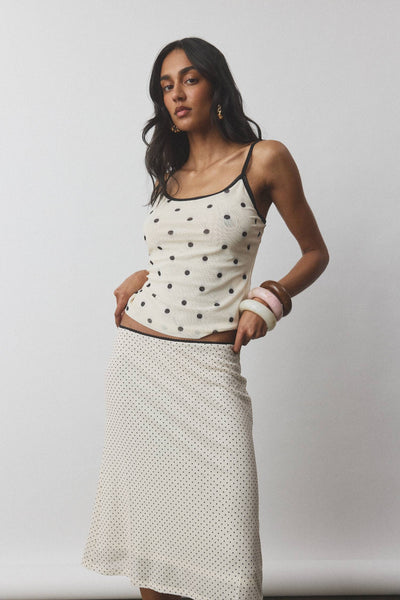 A full-length front studio shot of a model showcasing the With Harper Lu Midi Skirt in Mesh Ivory Polka, highlighting the mid-waist tailoring and fluid, subtle A-line flare at the hem.