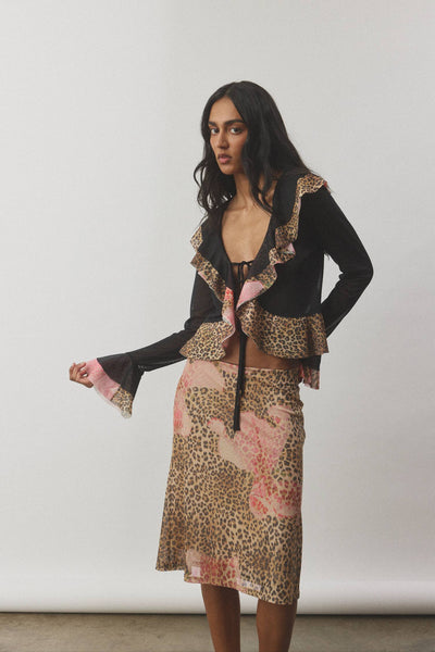 A clean, isolated studio image presenting the frill cardigan from the front on a model, showcasing how the two center front ties secure the lightweight sheer fabric.