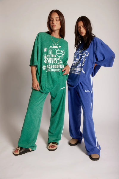 Two models posing together wearing Sabbi The Very Oversized Margie Tee in Forest Green and Royal Blue with matching track pants.