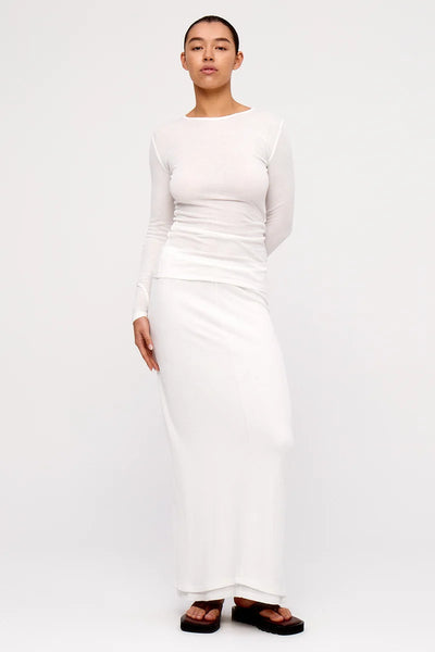 Three-quarter front view of a model wearing the white Zulu & Zephyr Rib Hemp Jersey Long Sleeve Top and matching long skirt with brown platform sandals.