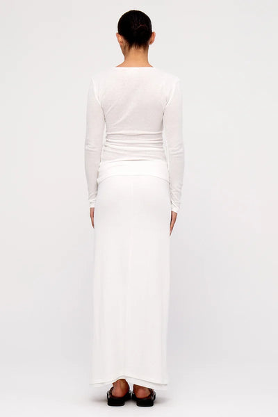 Full-length back view of a model wearing the slim-fit Zulu & Zephyr Rib Hemp Jersey Long Sleeve Top in white, paired with a matching white maxi skirt.