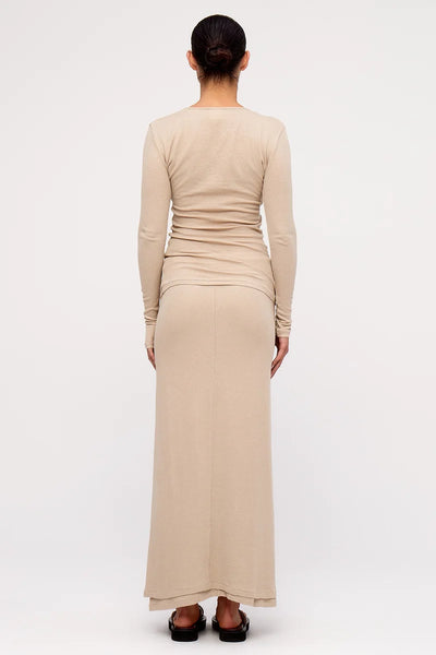 Full-length back view of a model wearing the Zulu & Zephyr Rib Hemp Jersey Long Sleeve Top and matching long skirt in husk beige, showing the slim silhouette and long sleeves.