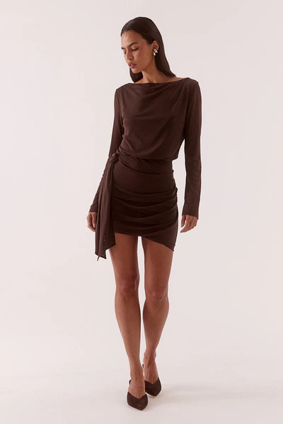 A full-length studio photograph of the model captured mid-stride at a slight angle, looking downwards. This dynamic shot highlights the fluidity of the premium mesh fabrication and the asymmetric bubble hemline as it moves.