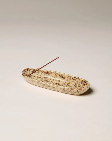 Studio product view of the Gentle Habits Collector Ceramic Incense Holder featuring a speckled leopard-pattern glaze holding an unlit incense stick against a plain background.