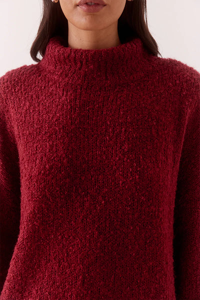 A macro close-up shot focusing on the tactile bouclé-style finish of the acrylic-wool blend loop yarn, showcasing the rich depth of the deep red tone.