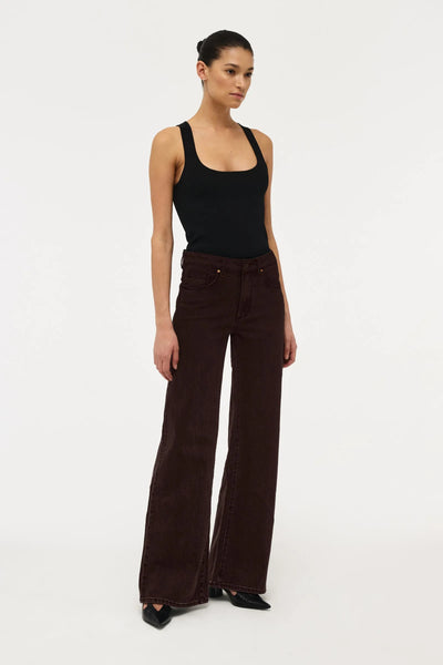 Three-quarter front view of Neuw Eva Wide dark brown jeans paired with a scoop neck black tank top and pointed black heels.