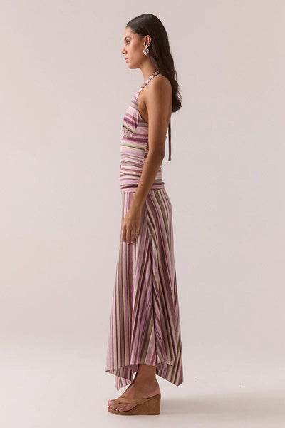Side profile view of a model showcasing the Vere Sarina halter maxi dress in orchid textured stretch mesh with a draped waist and asymmetrical hemline.
