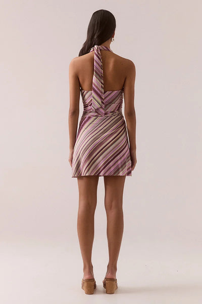 Full-length back view of a model showcasing the open back and halter neck tie detailing of the Vere Myriad Sarina orchid mini dress in textured stretch mesh.