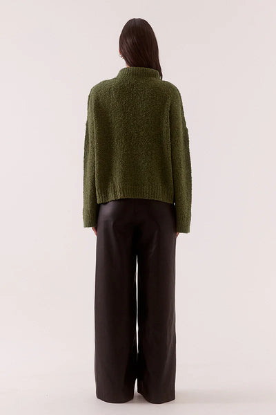 A full back view of the khaki Verse Sweater on a model, emphasizing the clean shoulder transitions and the rich, uniform texture of the earthy loop yarn fabric.