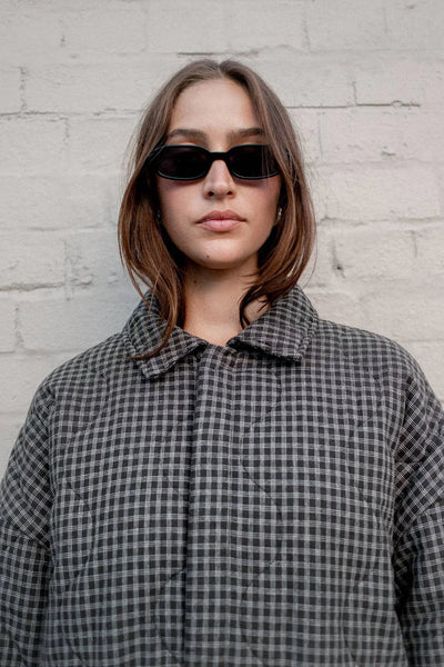 A close-up portrait focusing on the upper half of the jacket, showing the collar detail and the intricate Espresso Check quilted texture.