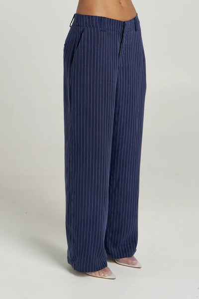 Three-quarter back view of model in the Summi Summi Navy Pinstripe Boss Pant, styled with a cropped matching long-sleeve shirt.