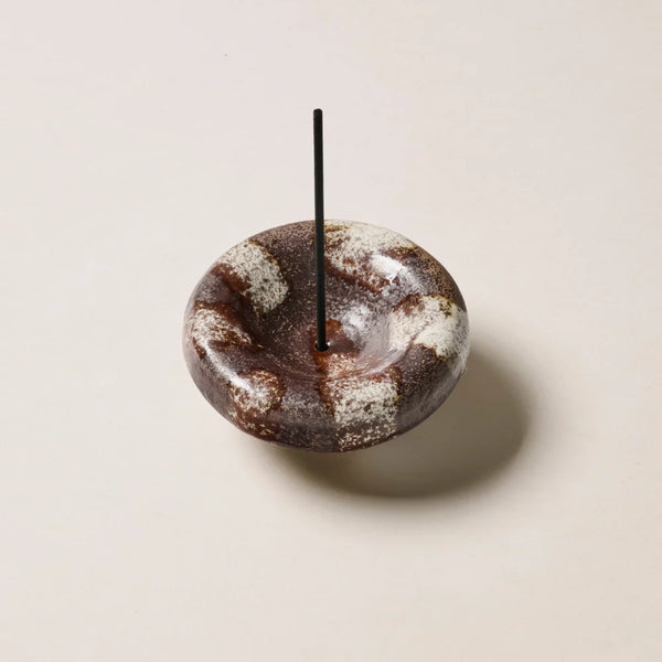 Studio product shot of the Gentle Habits Vessel Incense Holder in Chocolate with a black incense stick inserted vertically into the center opening on a neutral background.