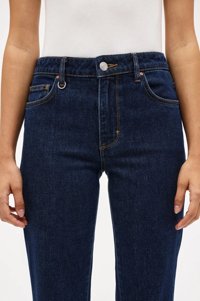A detailed, front close-up shot of the mid-rise top block of the Freja Straight in Paris. This image highlights the deep dark indigo wash of the organic cotton denim, the contrast stitching, the classic five-pocket design, and Neuw's signature fob ring detail attached to the front belt loop.