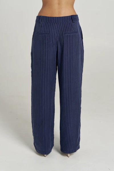 Side profile studio shot of model wearing the Summi Summi Navy Pinstripe Boss Pant and matching oversized suit blazer.