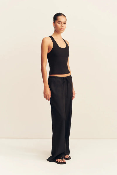 Three-quarter standing view of a model styled in the black Shona Joy Castro suiting pants featuring front pintucks, a drawstring waist, and wide legs.