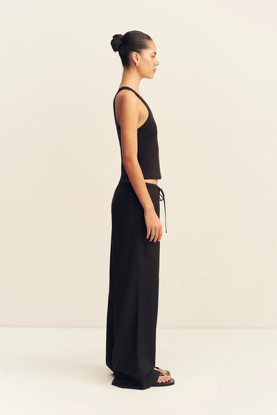 Side profile view of a model wearing the black Shona Joy Castro relaxed wide-leg suiting trousers with an adjustable drawstring waist.