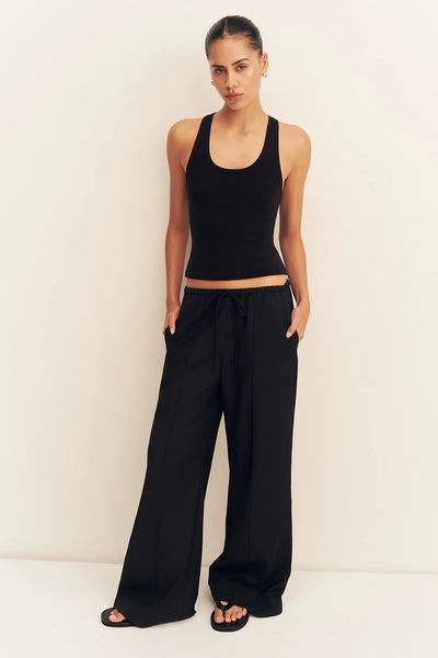 Front full-length view of a model posing with hands in pockets wearing the black Shona Joy Castro drawstring suiting pants and a fitted black tank top.