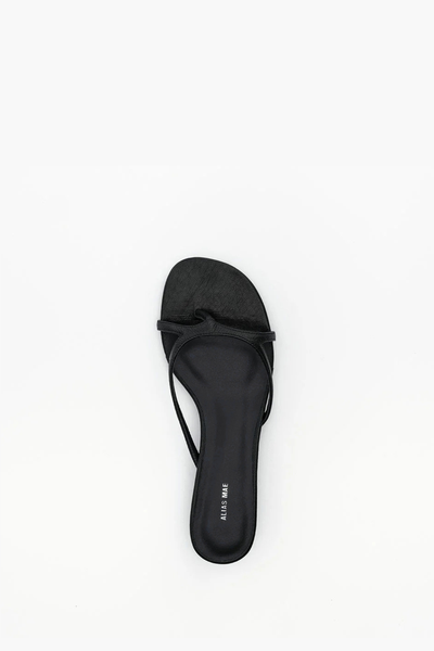 Top-down view of the Alias Mae Bodie sandal in black tumble leather, showcasing the asymmetrical strappy design and toe-loop silhouette on a dark footbed.