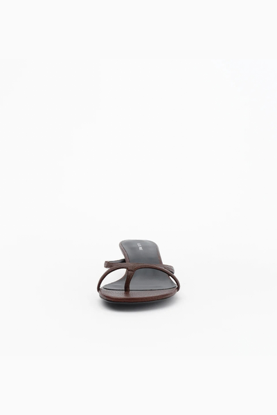 Front-facing studio shot of the chocolate brown leather sandal, emphasizing the toe loop and delicate strap placement across the foot.