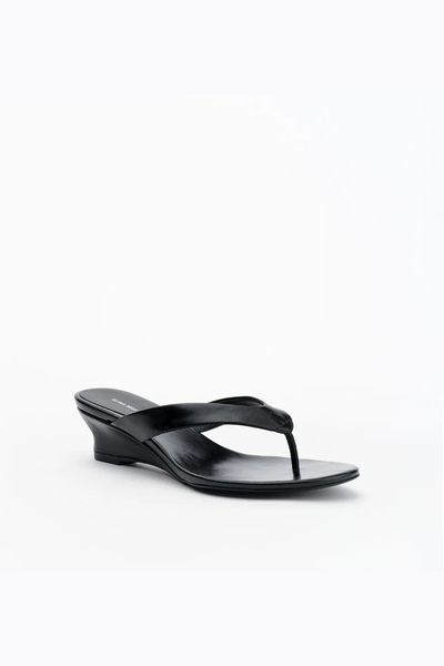 Front three-quarter view of the black leather thong sandal, highlighting the curved strap and the 45mm sculpted wedge heel.