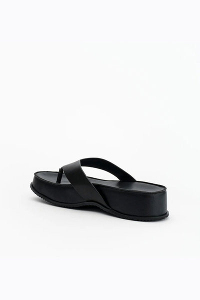 Front three-quarter view of the black leather thong sandal, highlighting the wide supportive strap and the 40mm chunky flatform sole.