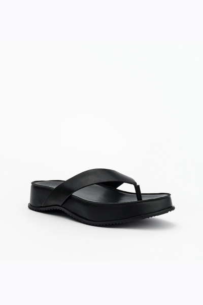 Low-angle three-quarter shot of the black leather flatform sandal, emphasizing the profile of the suede platform and wrapped rubber outsole.