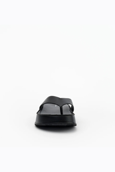 Front-facing low-angle view of the slip-on sandal, showcasing the clean lines of the wide leather strap and rounded toe