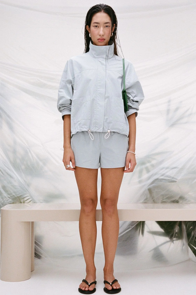 Full-length studio front shot of a model wearing the pale blue Arcaa Movement Addie Short paired with the matching high-neck Addie Jacket as a coordinated set.