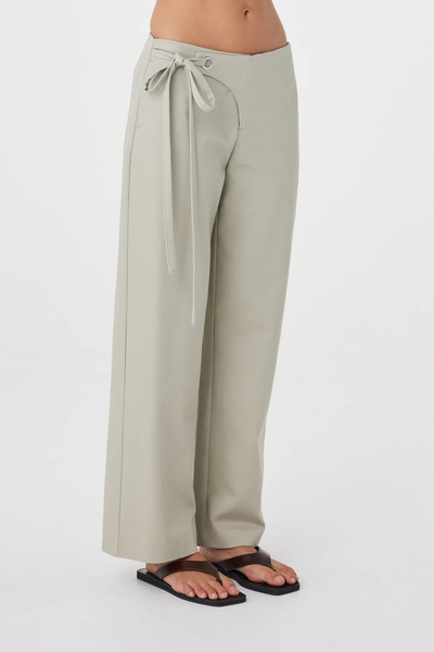 Close-up studio side view of the light sage Arcaa Movement Lucia Tie Pant showcasing the waist tie detail, overlap fly, and relaxed straight-leg silhouette.