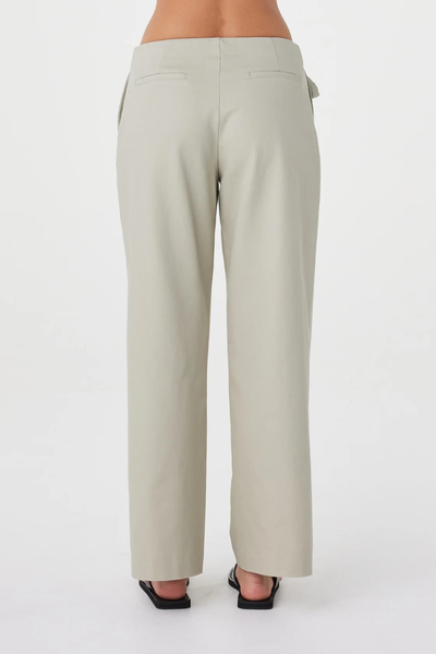 Cropped studio back view of the light sage Arcaa Movement Lucia Tie Pant, showing the clean rear fit and non-functional back welt pockets.