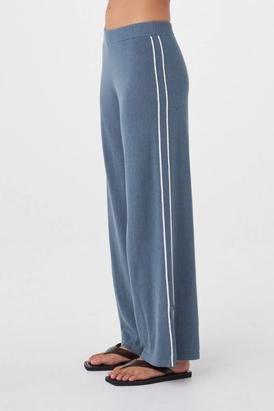 Close-up side view of the storm blue Arcaa Movement Pippa Pant 2.0 showcasing the ribbed waistband, dual cream side stripes, and wide-leg cut with side hem slit.