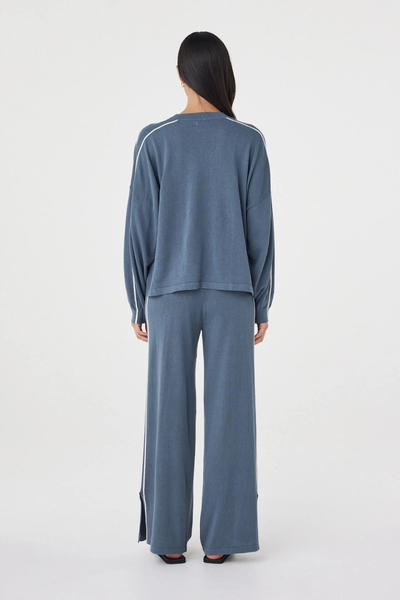 Full-length studio back view of a model wearing the storm blue Arcaa Movement Pippa Pant 2.0 set, showcasing the relaxed wide-leg fit and side hem split detail.
