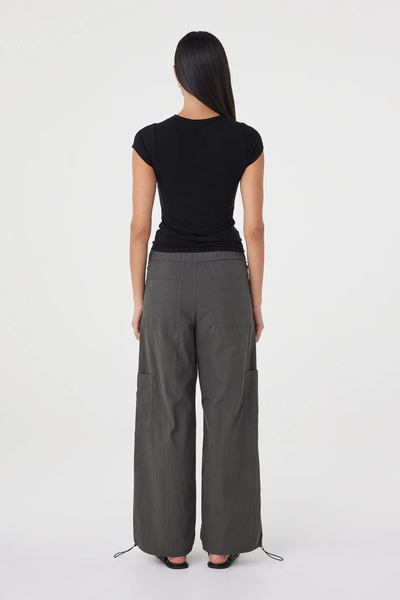 Full-length studio back view of a model wearing the black Arcaa Movement Robbie Top, showing the seamless back fit and cap sleeve coverage.