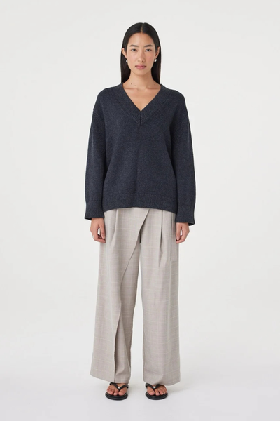 Full-length front view of a model wearing the soft cotton-wool blend Arcaa Movement Zenya Sweater in dark grey marle with loose pleated trousers.