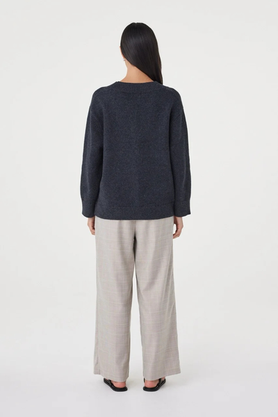 Full-length studio back view of a model wearing the dark grey marle Arcaa Movement Zenya Sweater, showcasing the relaxed silhouette and ribbed hem finish.