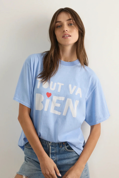 Studio close-up portrait of a model wearing the sky blue "Tout Va Bien" boyfriend tee and denim jeans.