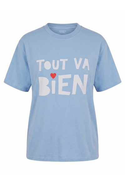 Flat product shot of the sky blue organic cotton boyfriend tee against a white background, featuring bold white "TOUT VA BIEN" lettering with a small red heart accenting the word "BIEN".