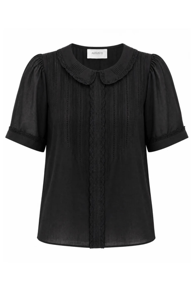 Studio e-commerce product display of the Auguste The Label Magdalena Blouse in Black against a stark white background. This flat-lay style front view showcases the intricate design details, including the Peter Pan collar, vertical pintucks, hand-done ladder stitching, embroidery, and delicate lace trim along the collar, center button placket, and sleeve cuffs.