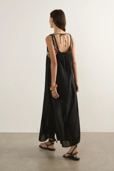 Studio rear view of a model wearing the black Amiah maxi dress, highlighting the scoop backline with a delicate tie closure and the flowing skirt.